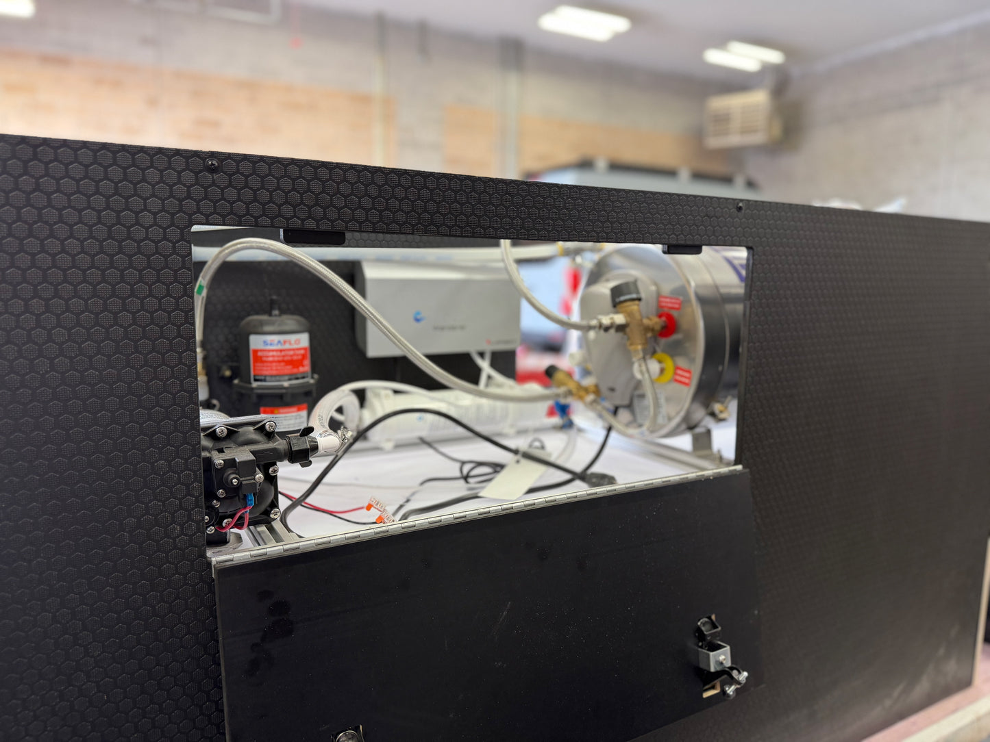 Plumbing cabinet open — HexPly door, heater, SEAFLO