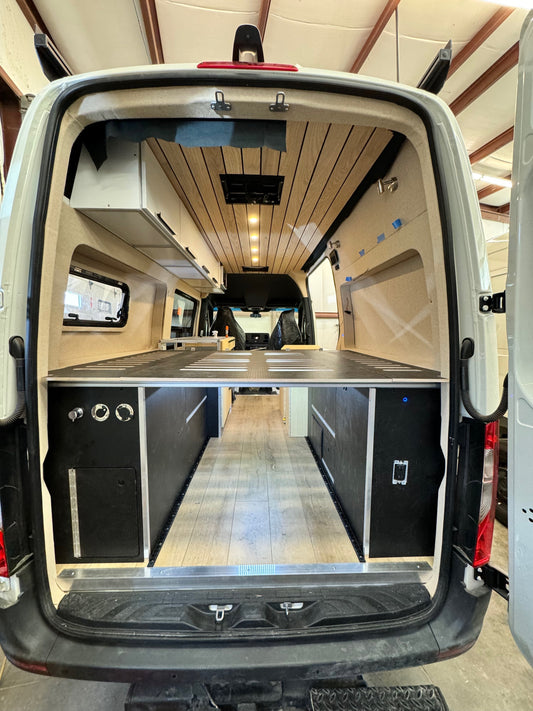 Rear of the van — plumbing and electrical cabinets under the slotted HexPly bed platform